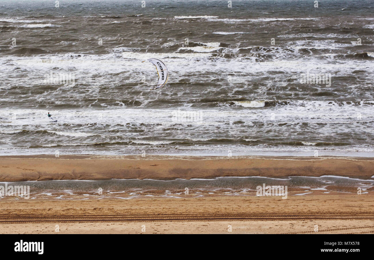 Niederlande, APRIL 2017: Die WINDIGEN kalten Sand Strand im Norden der Europa. Es gibt eine kleine Zahl von kitersurfer in die Wellen. Stockfoto