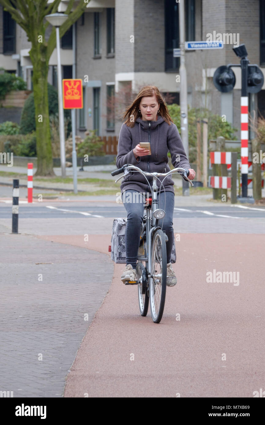 Junge Frau von seinem Smartphone abgelenkt, der beim Reiten sein Fahrrad rund um die Stadt Stockfoto
