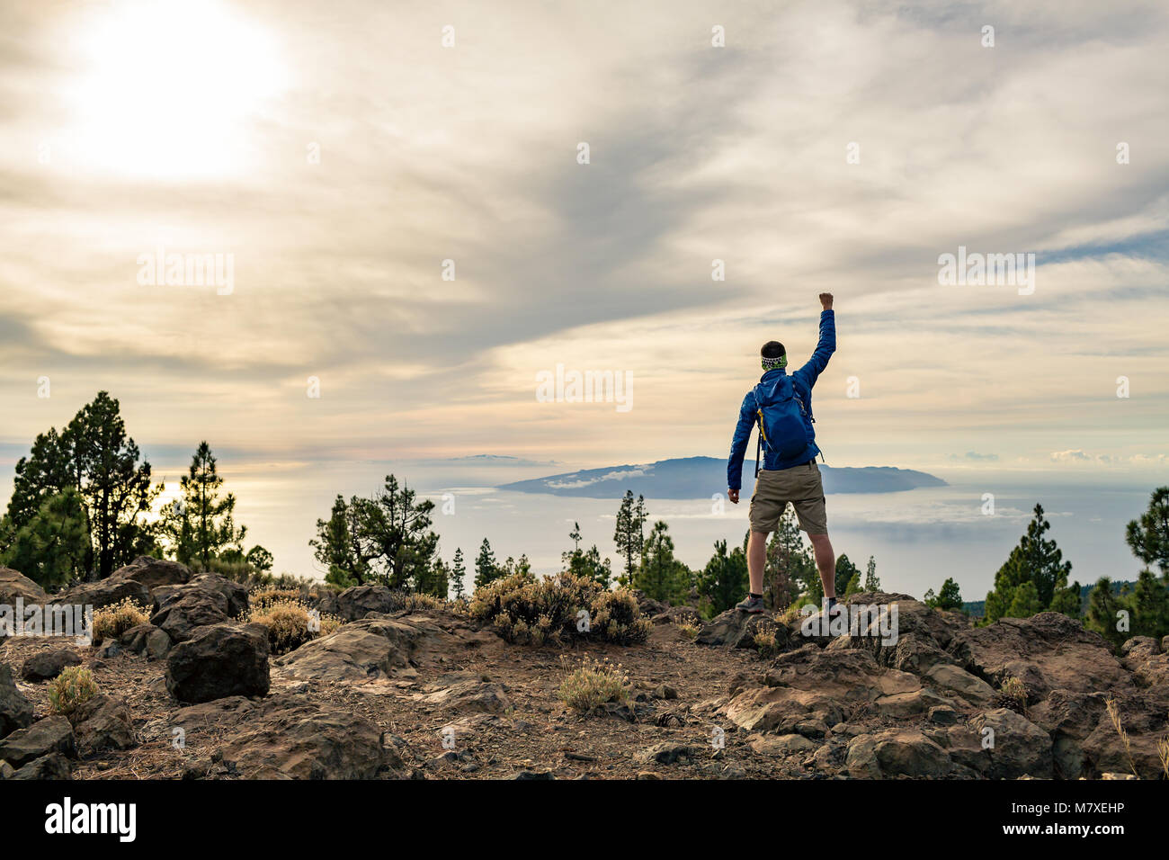 Mann feiern Sonnenuntergang an der Blick in die Berge. Trail Runner, Wanderer oder Bergsteiger erreicht oben auf einem Berg, geniessen Sie inspirierende Landschaft auf felsigen Stockfoto