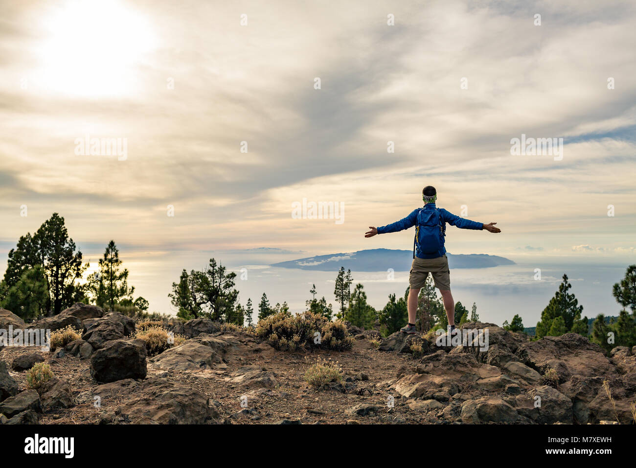 Mann feiern Sonnenuntergang an der Blick in die Berge. Trail Runner, Wanderer oder Bergsteiger erreicht oben auf einem Berg, geniessen Sie inspirierende Landschaft auf felsigen Stockfoto