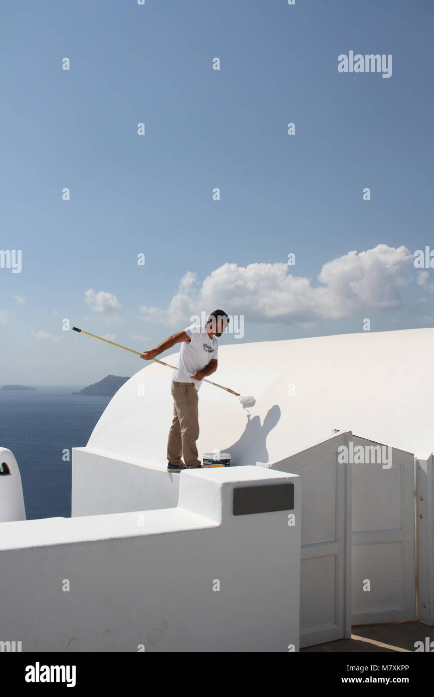 Ein Mann, der das Dach eines typischen weißen Haus in Oia, Santorini, Kykladen, Griechenland. Stockfoto