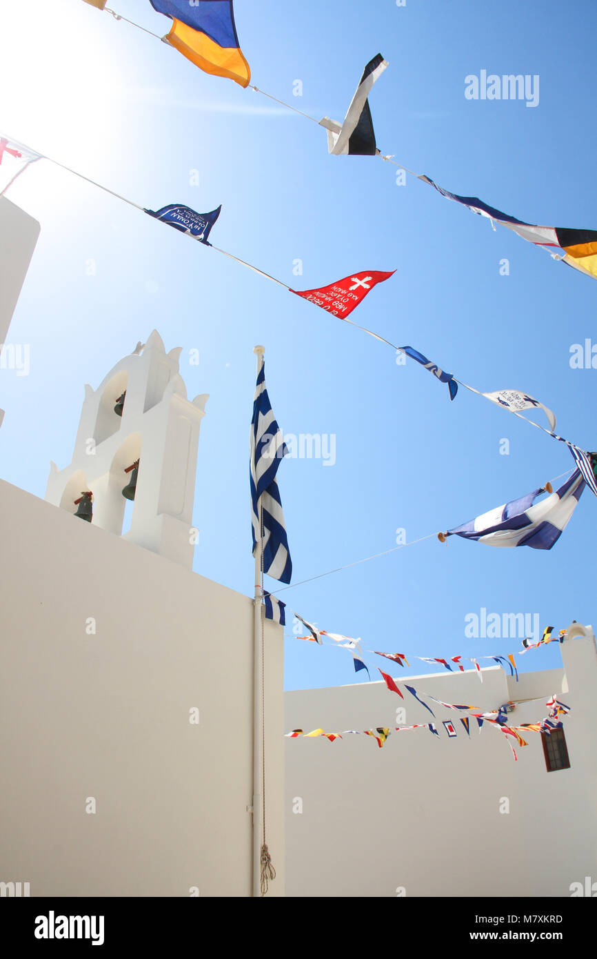 Flaggen verschiedener Länder winken auf weiße Kirche in Oia, Santorini, Kykladen, Griechenland. Stockfoto