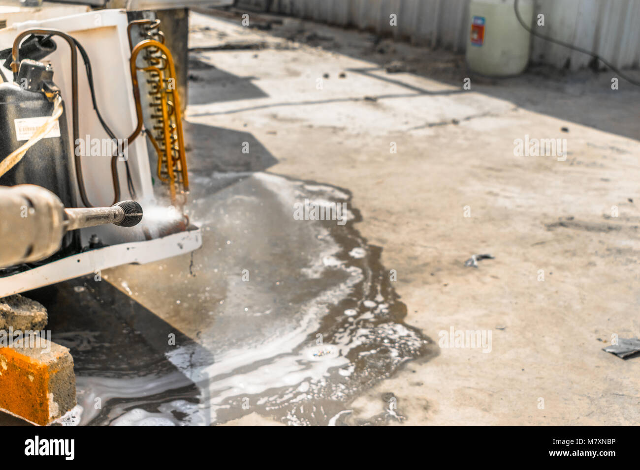 Einen professionellen Elektriker ist die Reinigung der Fenster Klimaanlage auf dem Dach eines Hauses mit seinem hohen Druck Wasser Pistole Stockfoto