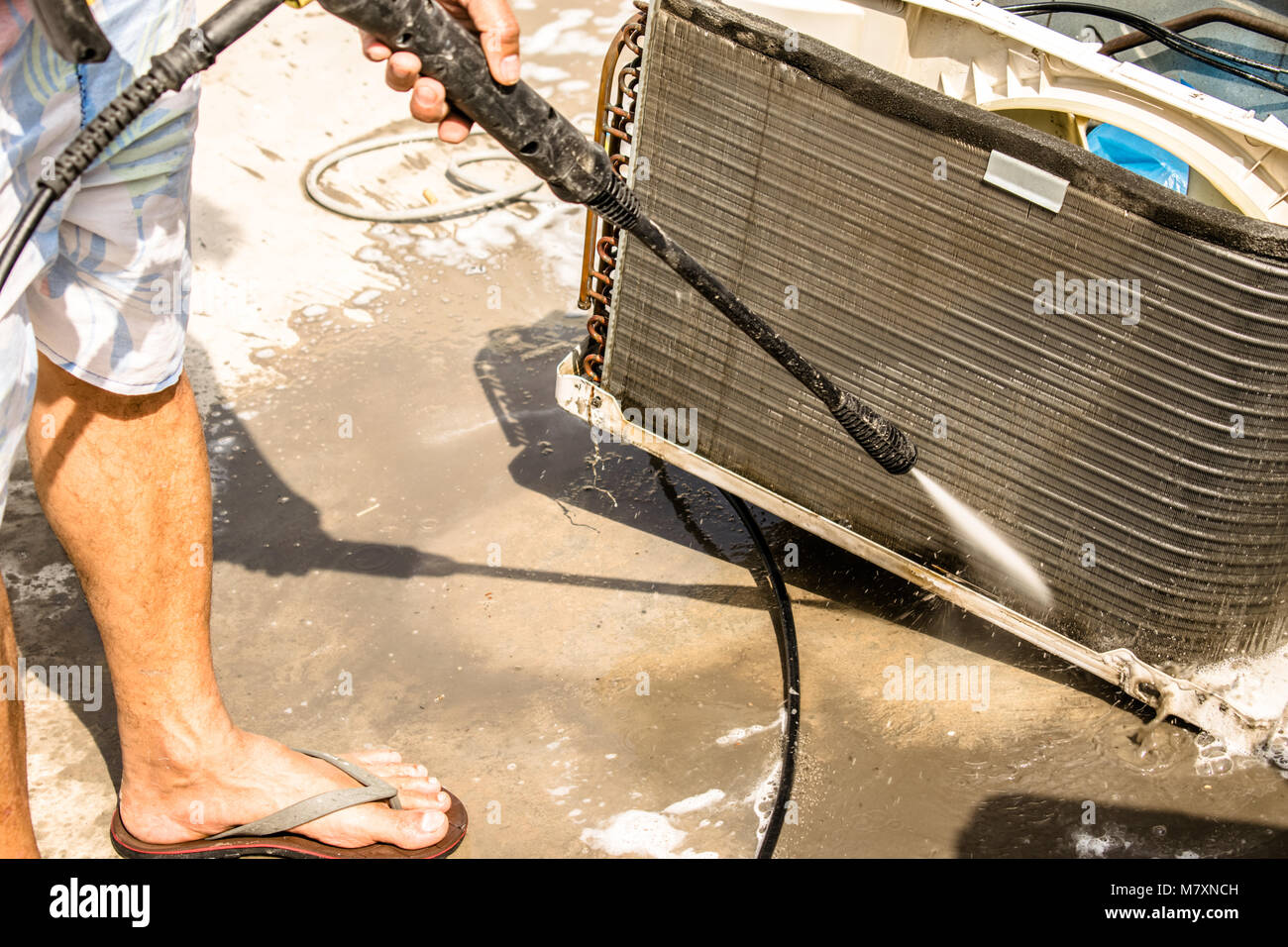 Einen professionellen Elektriker ist die Reinigung der Fenster Klimaanlage auf dem Dach eines Hauses mit seinem hohen Druck Wasser Pistole Stockfoto