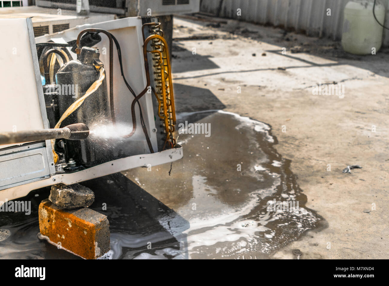 Einen professionellen Elektriker ist die Reinigung der Fenster Klimaanlage auf dem Dach eines Hauses mit seinem hohen Druck Wasser Pistole Stockfoto