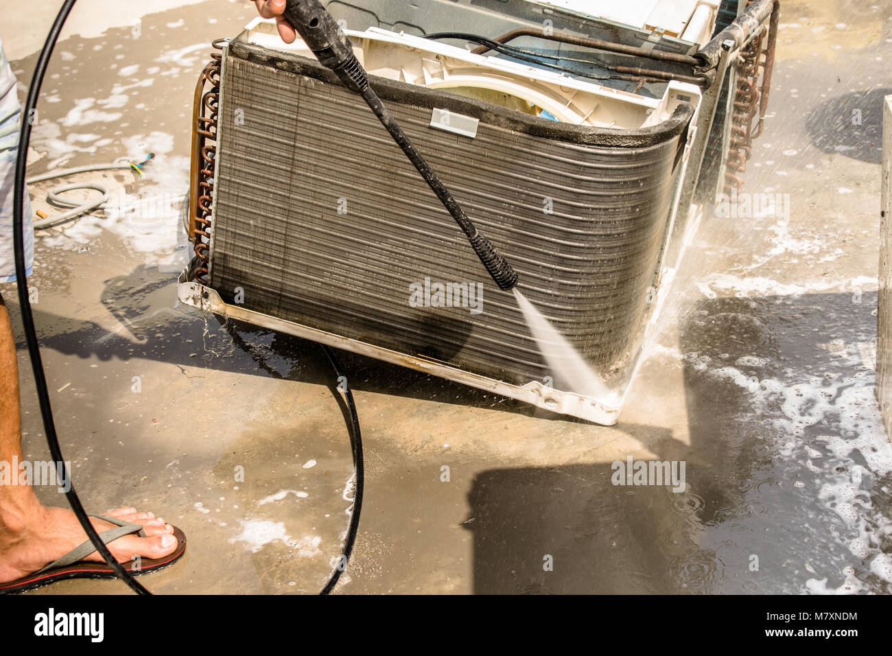 Einen professionellen Elektriker ist die Reinigung der Fenster Klimaanlage auf dem Dach eines Hauses mit seinem hohen Druck Wasser Pistole Stockfoto