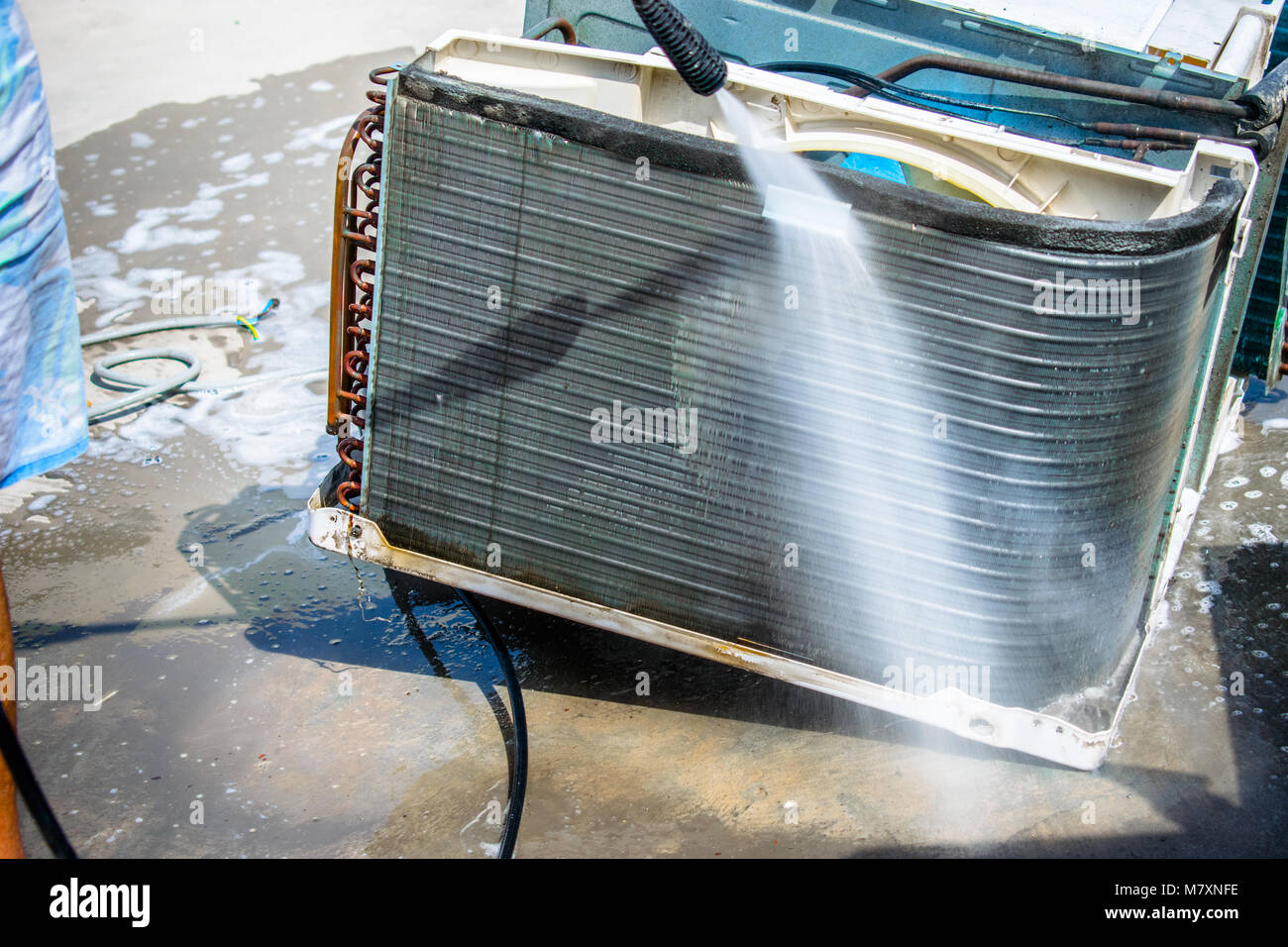 Einen professionellen Elektriker ist die Reinigung der Fenster Klimaanlage auf dem Dach eines Hauses mit seinem hohen Druck Wasser Pistole Stockfoto