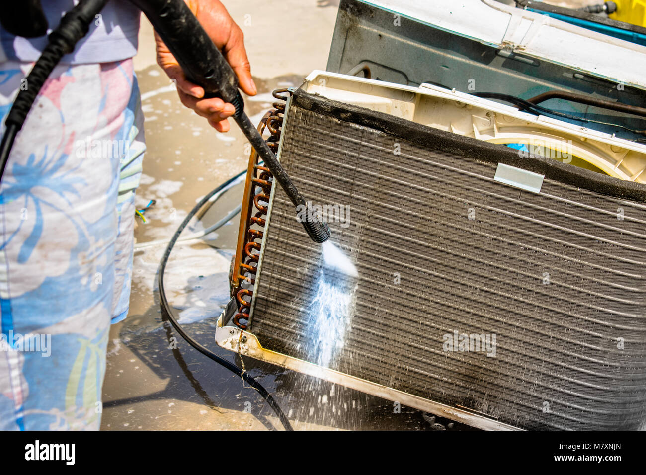 Einen professionellen Elektriker ist die Reinigung der Fenster Klimaanlage auf dem Dach eines Hauses mit seinem hohen Druck Wasser Pistole Stockfoto