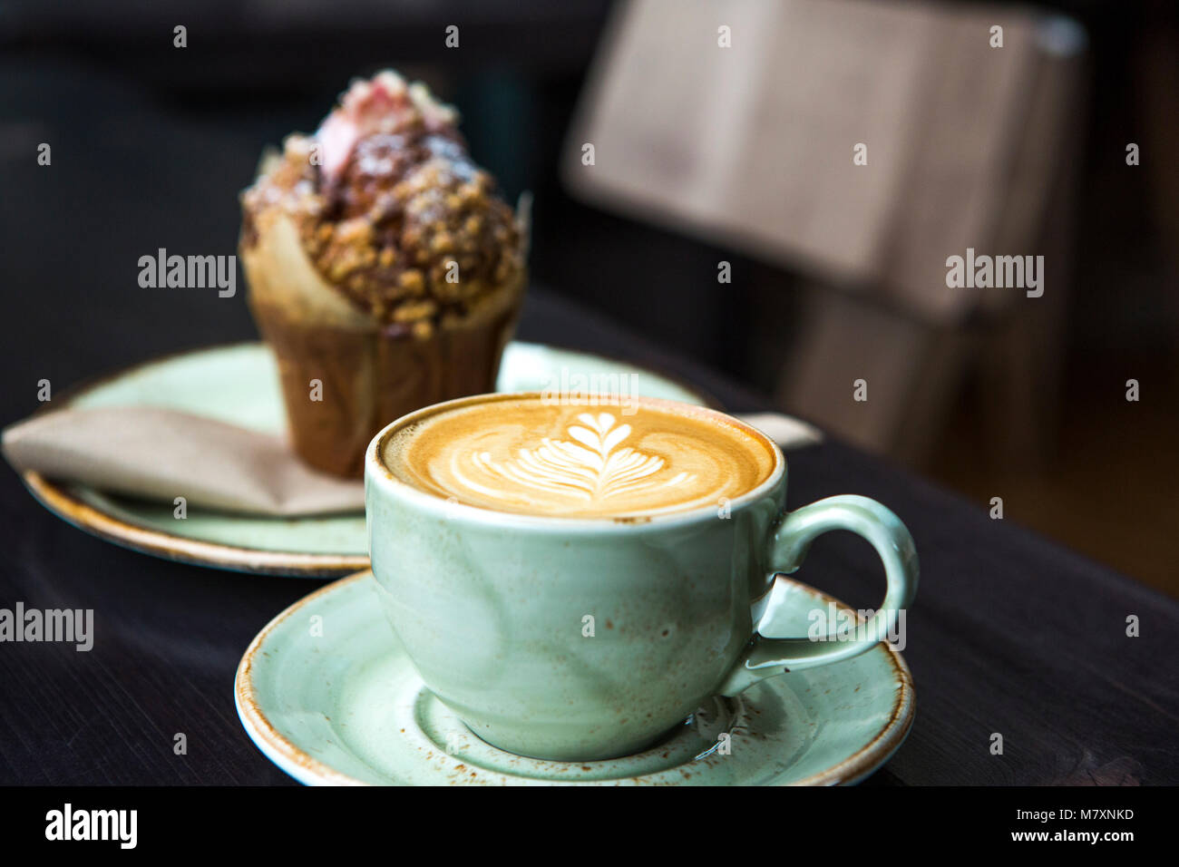 Cappuccino in grünem Kaffee Tasse und Untertasse mit Muffin. Stockfoto