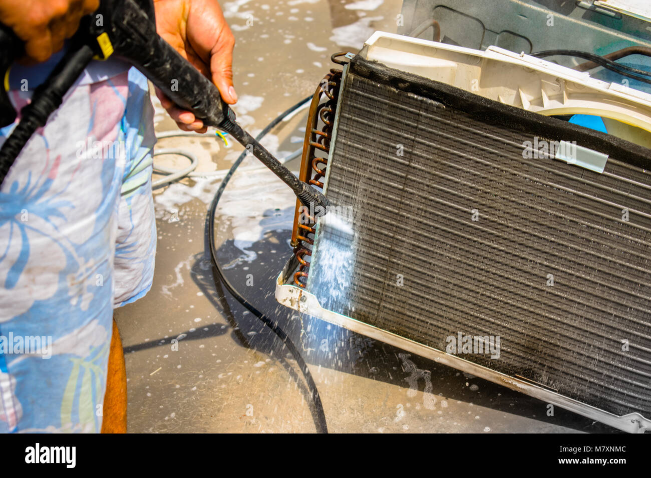 Einen professionellen Elektriker ist die Reinigung der Fenster Klimaanlage auf dem Dach eines Hauses mit seinem hohen Druck Wasser Pistole Stockfoto