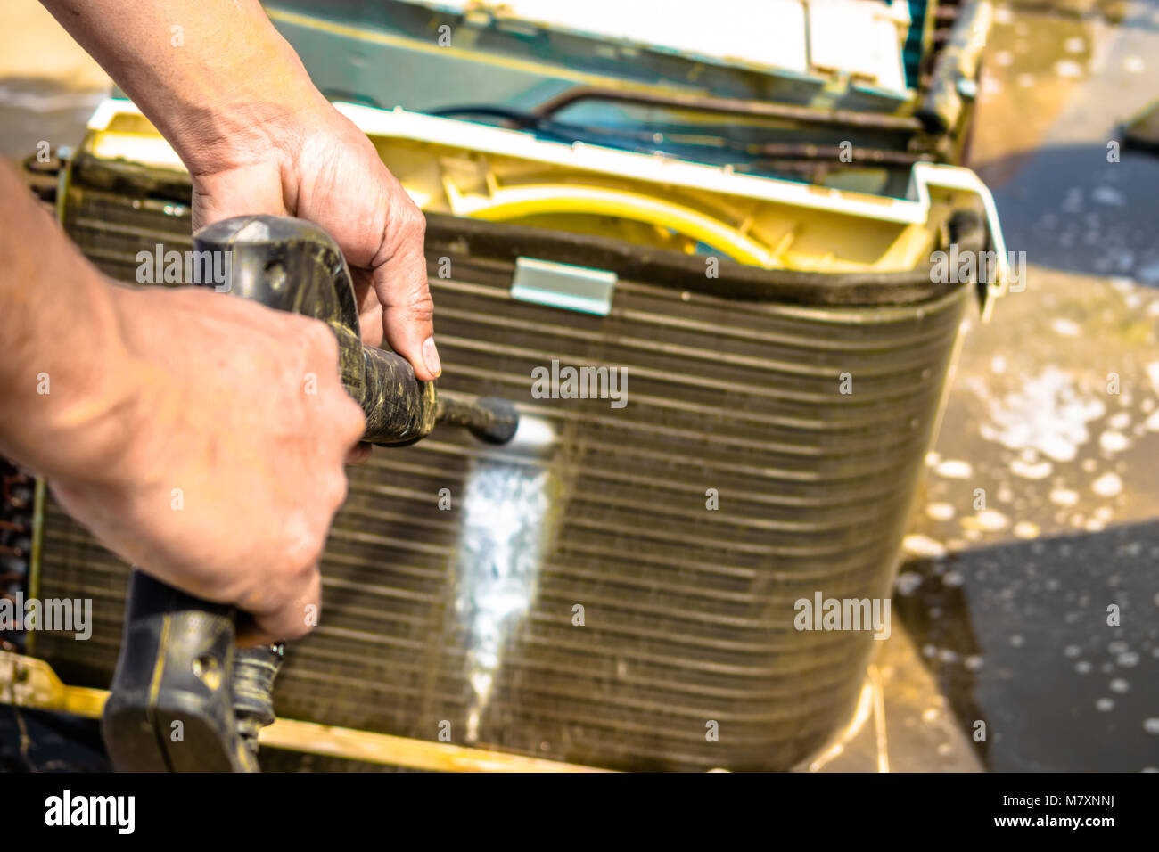 Einen professionellen Elektriker ist die Reinigung der Fenster Klimaanlage auf dem Dach eines Hauses mit seinem hohen Druck Wasser Pistole Stockfoto