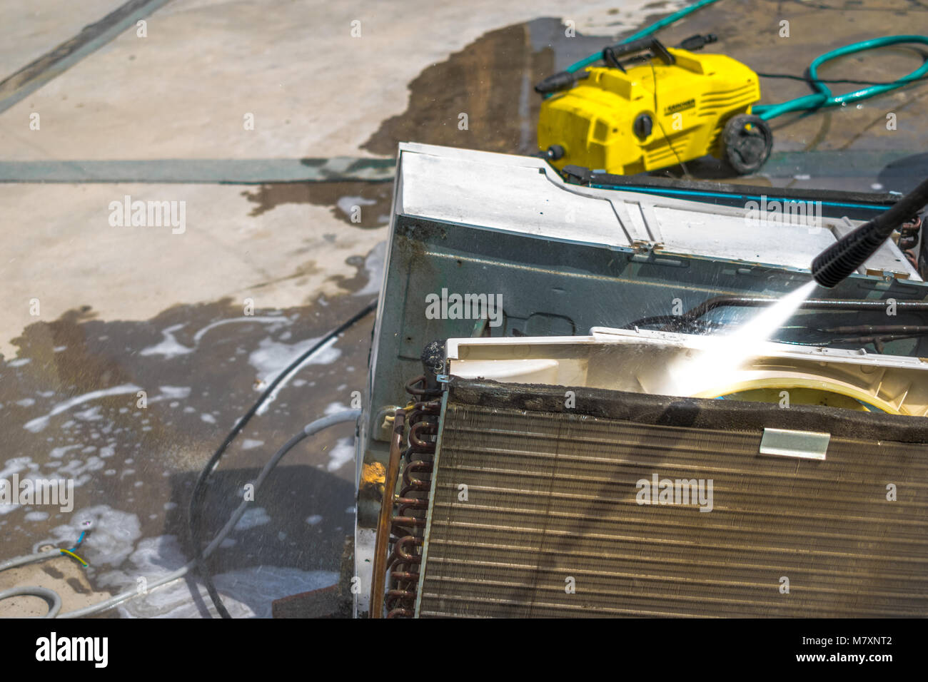 Einen professionellen Elektriker ist die Reinigung der Fenster Klimaanlage auf dem Dach eines Hauses mit seinem hohen Druck Wasser Pistole Stockfoto