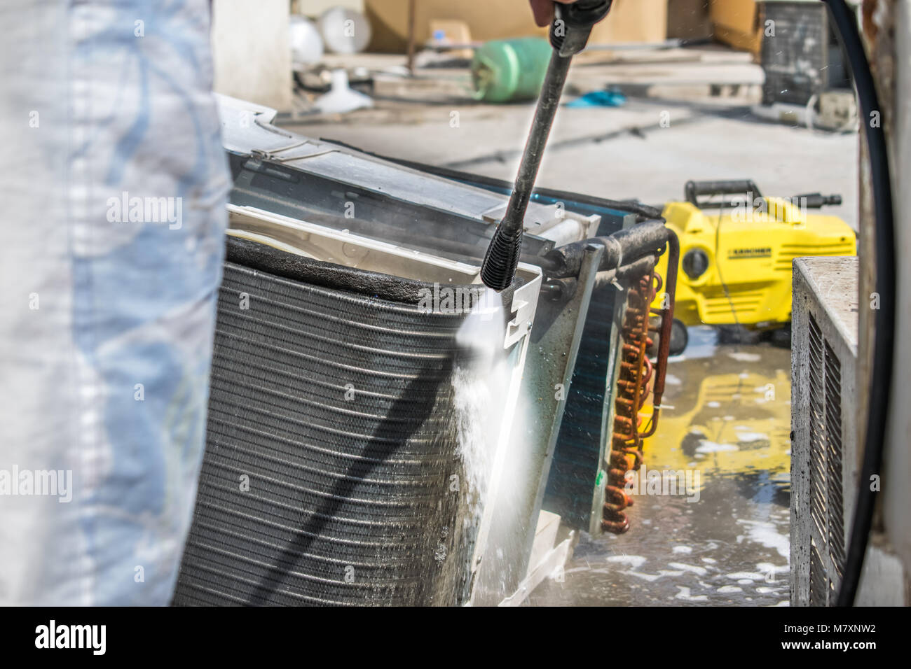 Einen professionellen Elektriker ist die Reinigung der Fenster Klimaanlage auf dem Dach eines Hauses mit seinem hohen Druck Wasser Pistole Stockfoto