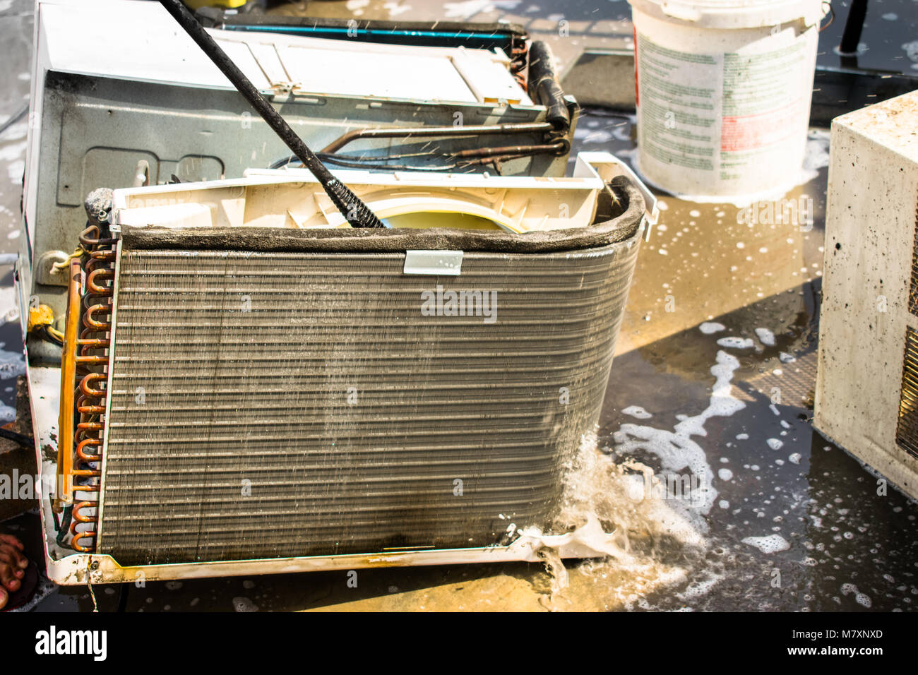 Einen professionellen Elektriker ist die Reinigung der Fenster Klimaanlage auf dem Dach eines Hauses mit seinem hohen Druck Wasser Pistole Stockfoto