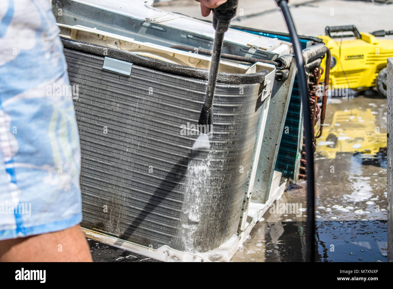 Einen professionellen Elektriker ist die Reinigung der Fenster Klimaanlage auf dem Dach eines Hauses mit seinem hohen Druck Wasser Pistole Stockfoto