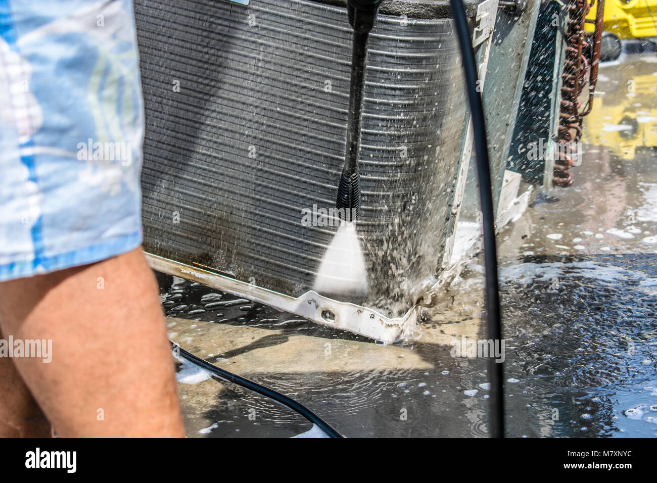 Einen professionellen Elektriker ist die Reinigung der Fenster Klimaanlage auf dem Dach eines Hauses mit seinem hohen Druck Wasser Pistole Stockfoto