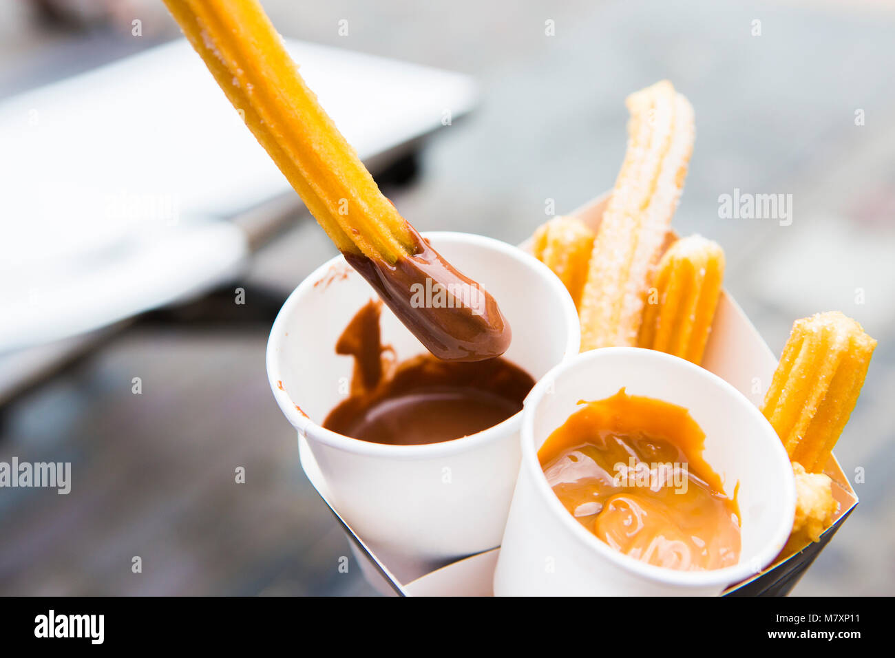 Street Food - Churros mit Karamellsauce und Schokoladensauce. Stockfoto