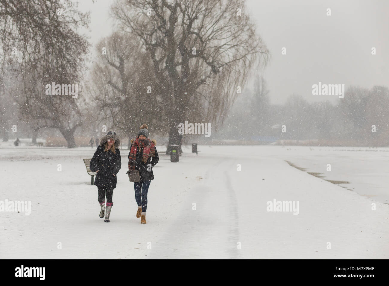 LONDON, UK: Zwei junge Frauen wandern in White's Regent's Park, während es schneit Stockfoto