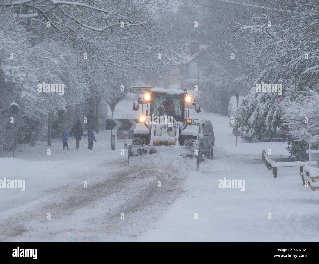 Ein Traktor mit einem Schneepflug Clearing eine Straße in Redditch, Worcestershire, Großbritannien. Stockfoto