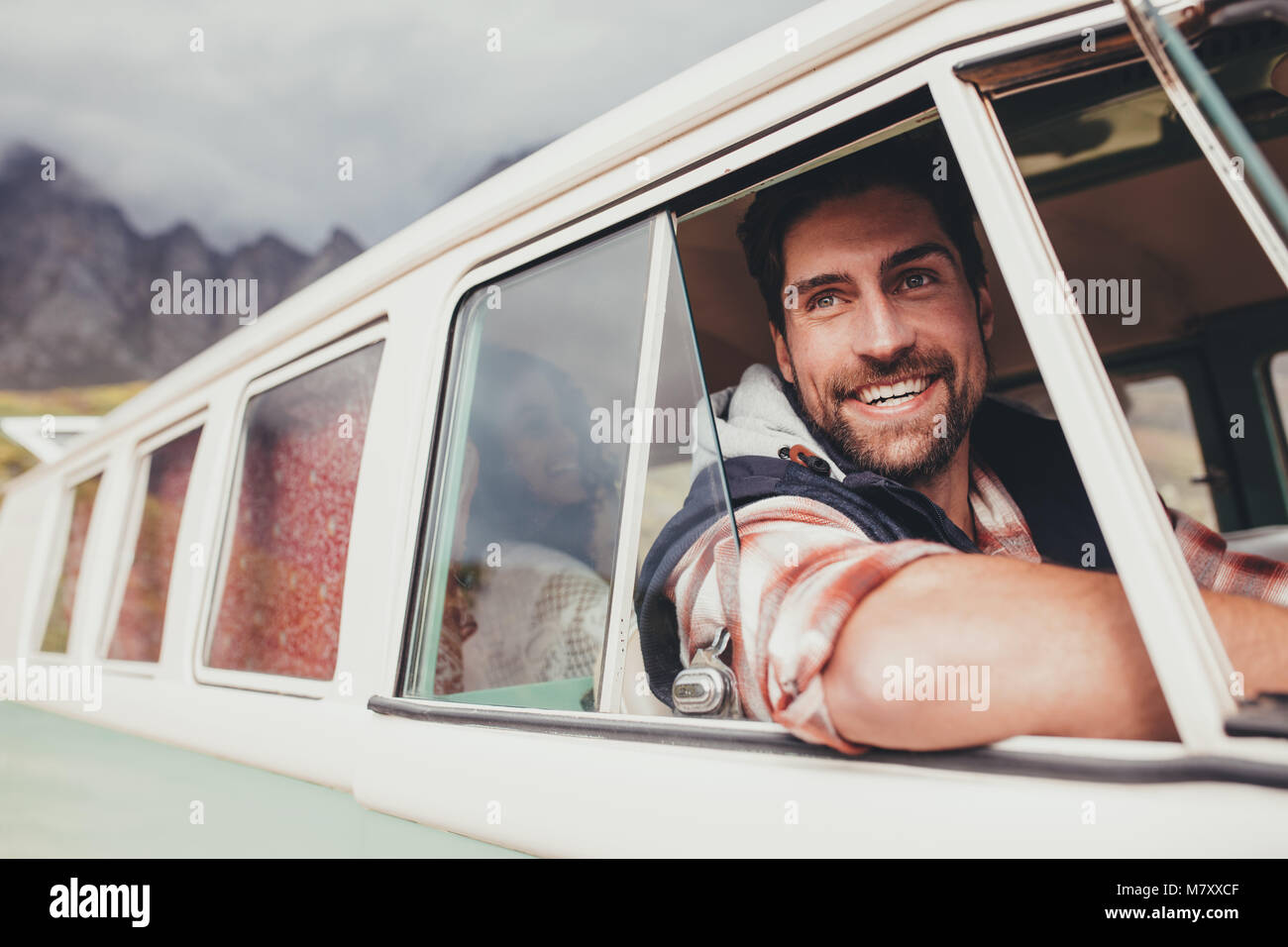 Lächelnder Mann, der einen Van und außerhalb. Stattlichen kaukasischen Mann auf einen Road Trip mit Freunden von einem alten minivan reisen. Stockfoto