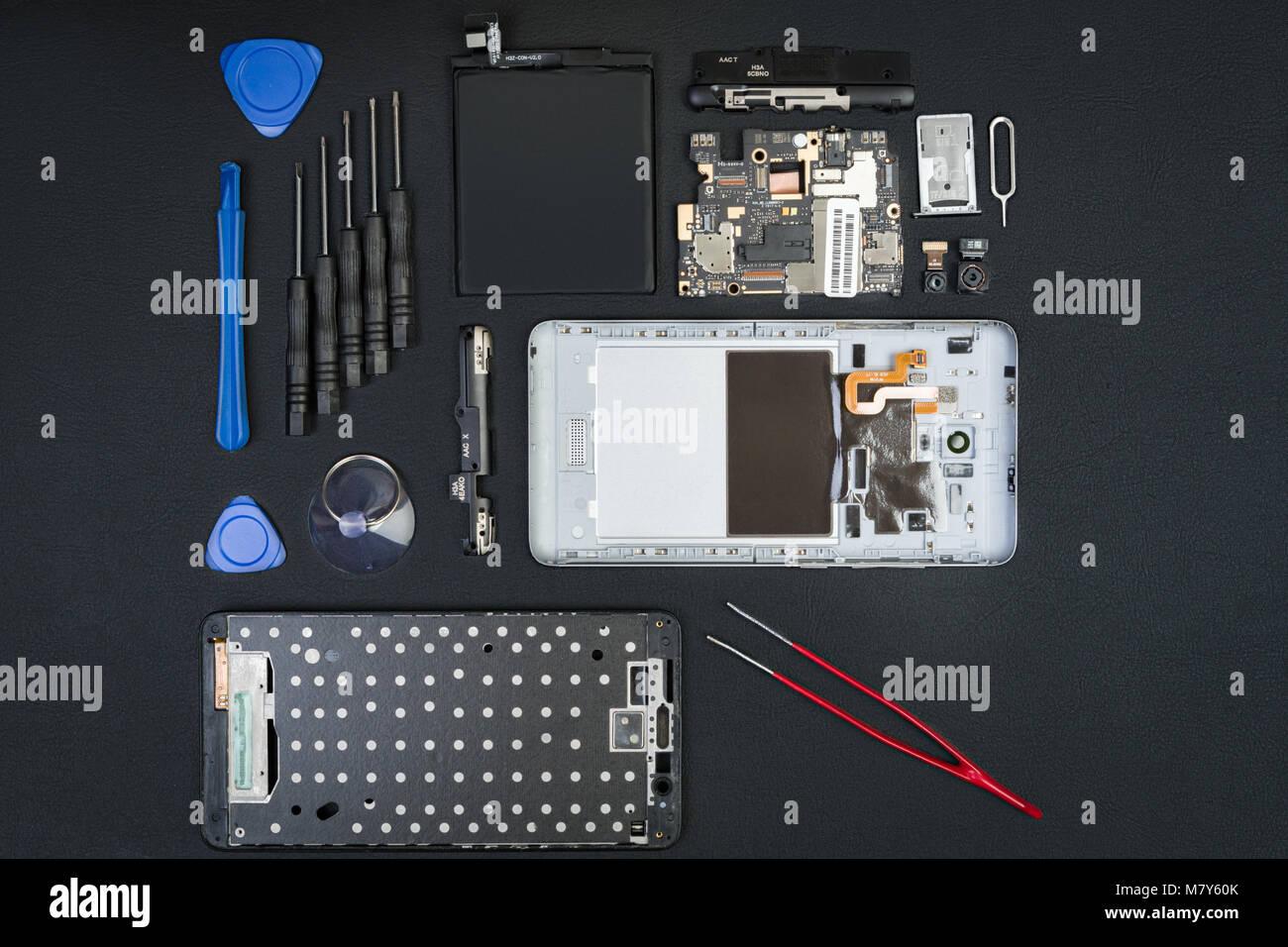 Die demontierten Smartphone, die mit der entfernten Bildschirm und Sonderwerkzeuge auf dem schwarzen Desktop. Handy Details im flatlay Stil. Stockfoto