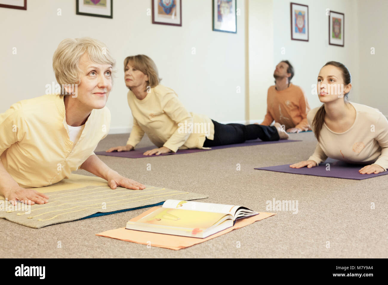 Menschen üben bhujanga Asana - Cobra in Yoga Klasse Pose von erfahrenen und zertifizierten Yogalehrer geleitet. Holding in Pose auf Ihre Yoga Matten auf Stockfoto