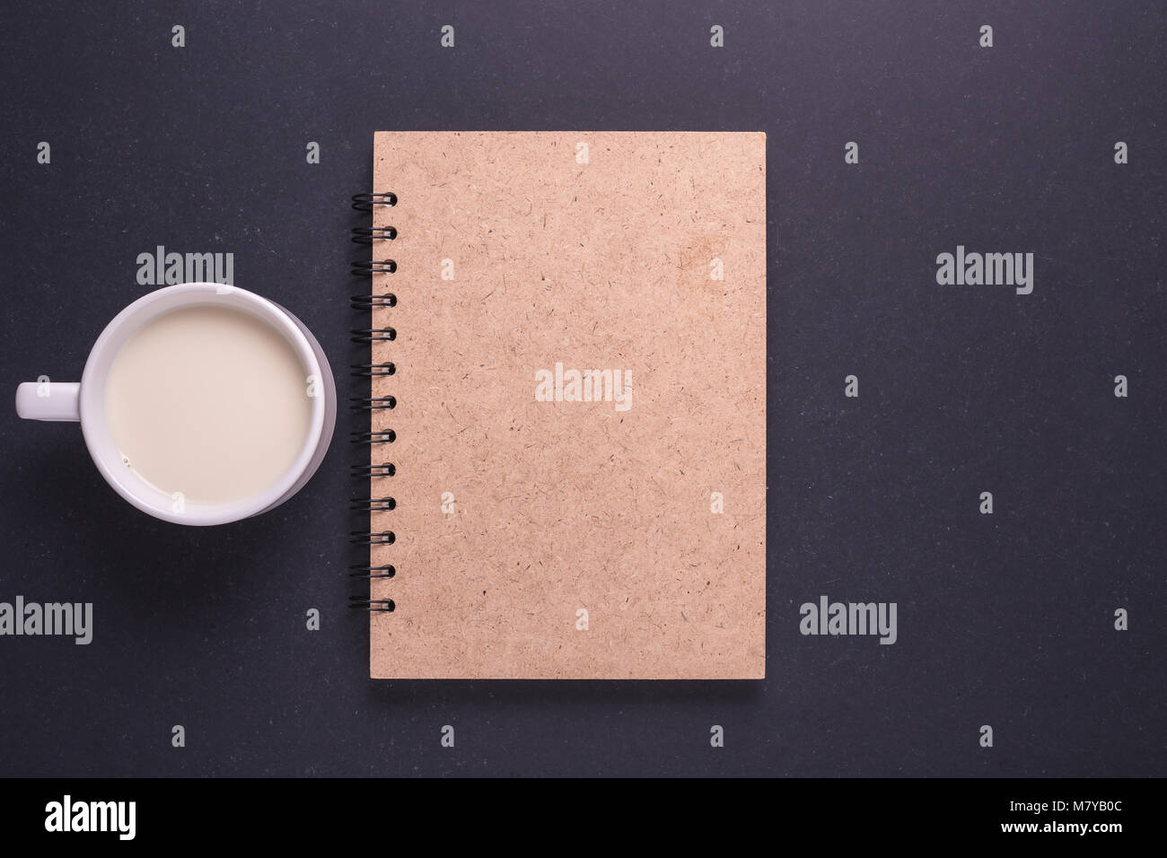 Milch in Glas weiß und braun Hinweis Buch über den schwarzen Stein Tabelle Hintergrund. Ansicht von oben und Studio shot Stockfoto