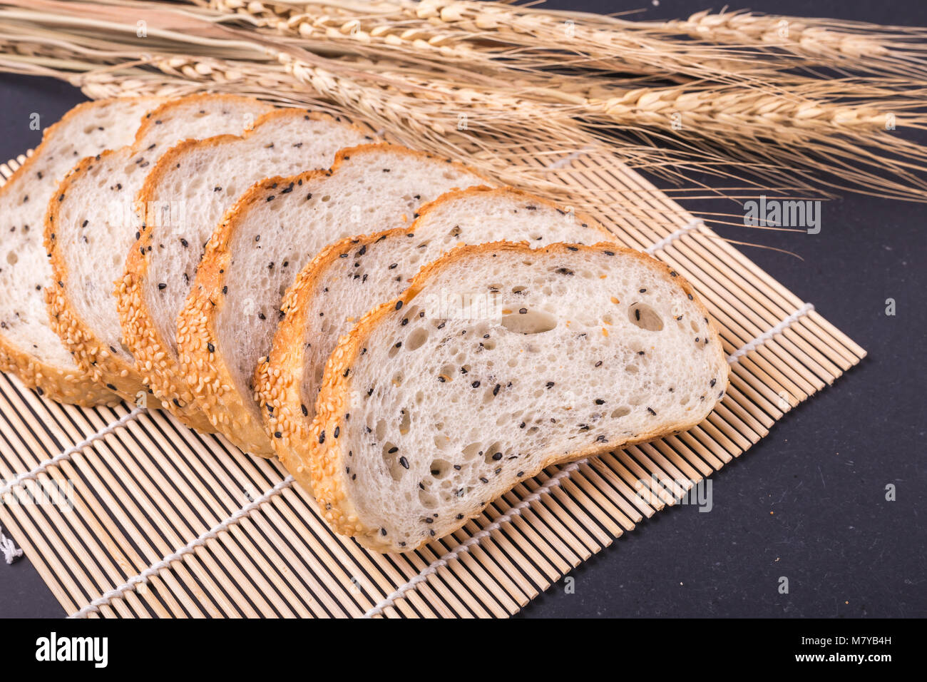 Scheiben frisches Weißbrot mit Sesam auf schwarzen Steintisch ...