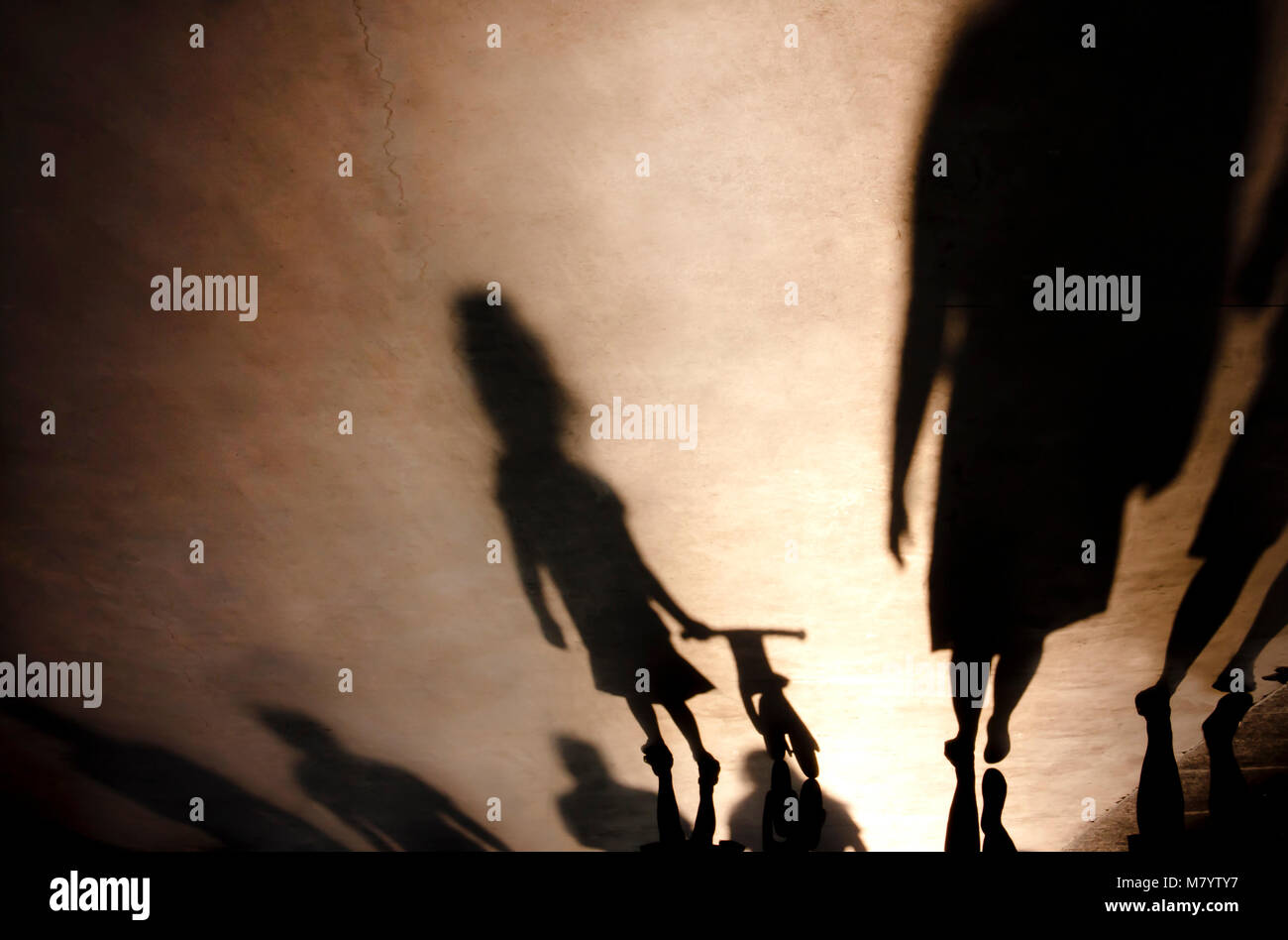Verschwommene Schatten Silhouetten der Familie mit einem kleinen Mädchen drücken Fahrrad auf misty Sommer promenade Stockfoto