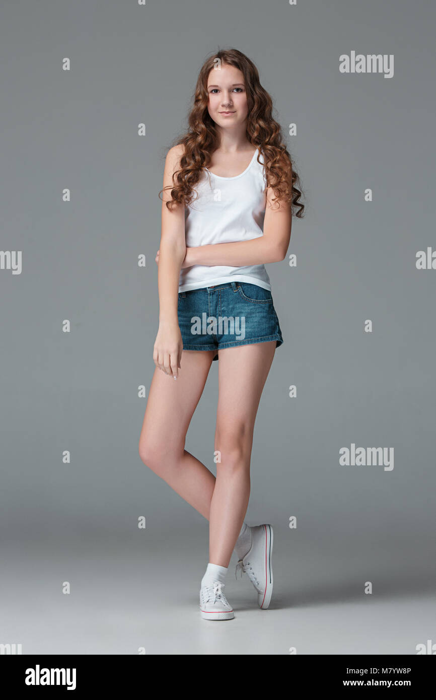 Die ganze Länge der junge schlanke Frauen Mädchen in Denim Shorts auf grauem Hintergrund Stockfoto