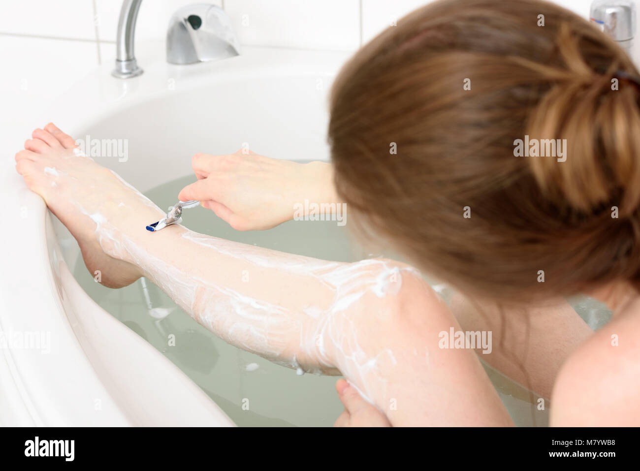 Kaukasische Frau rasieren ihr Bein in Ihrer Badewanne. Detail der Bein rasiert werden. Stockfoto