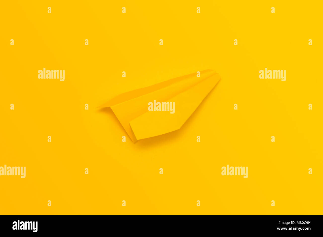Gelb origami Flugzeug auf einem gelben Hintergrund. Blick von oben. Stockfoto