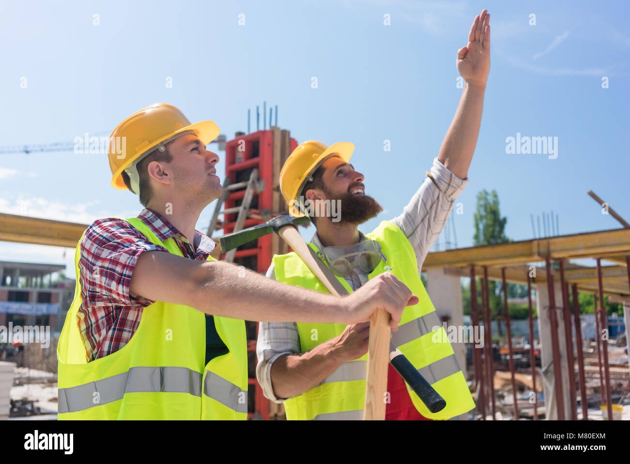 Entschlossene junge Arbeitnehmer nach oben zeigen, während sich die Höhe eines Gebäudes Stockfoto