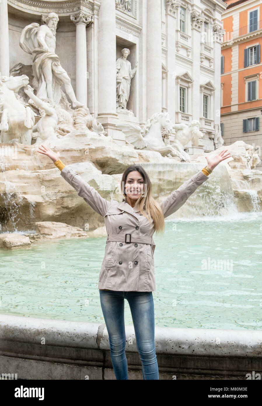 Junge hübsche Frauen kaukasischen Touristische lächelnd die Arme mit dem Trevi Springbrunnen im Hintergrund, Rom monument Sehenswürdigkeiten Italien Stockfoto