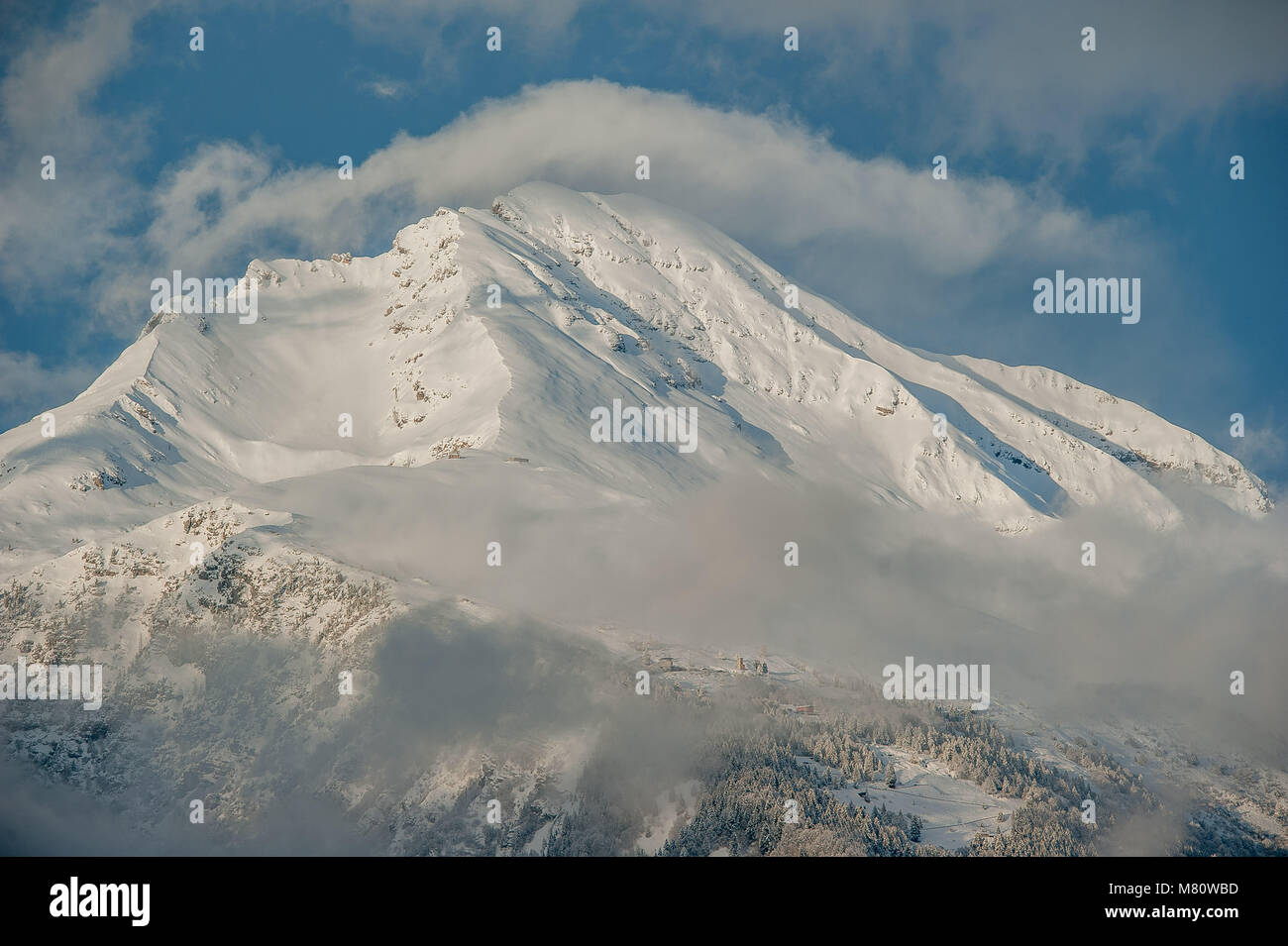 Die Berge, die sich aus den verschneiten Wolken Stockfoto