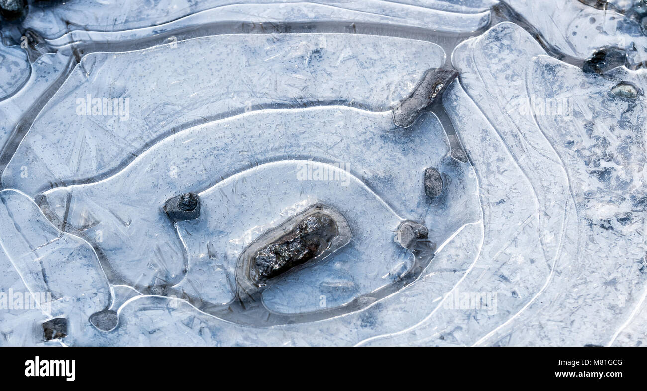 Schlammloch über mit weißen Eiskristallen, Ringe gefroren, und Felsen sichtbar Stockfoto