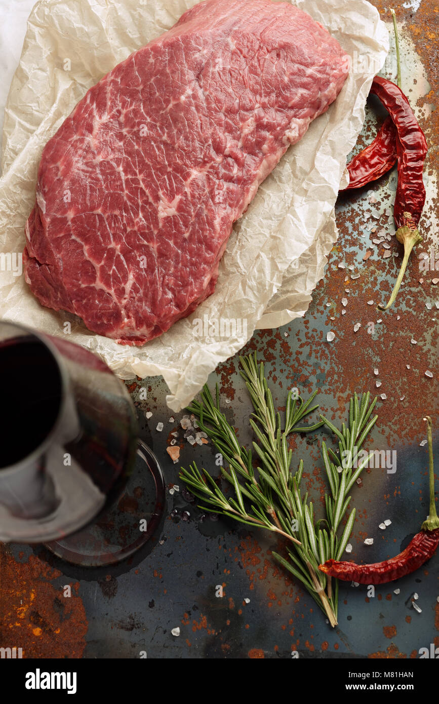 Raw Marmor Rindfleisch, Rosmarin, getrockneter Chili, und Rotwein auf einem rustikalen Tisch Stockfoto