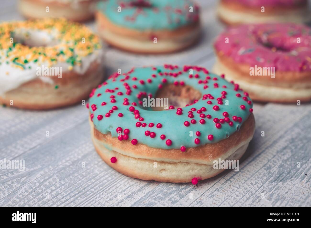 Donuts mit bunter Zuckerglasur auf einem hölzernen Hintergrund. Stockfoto