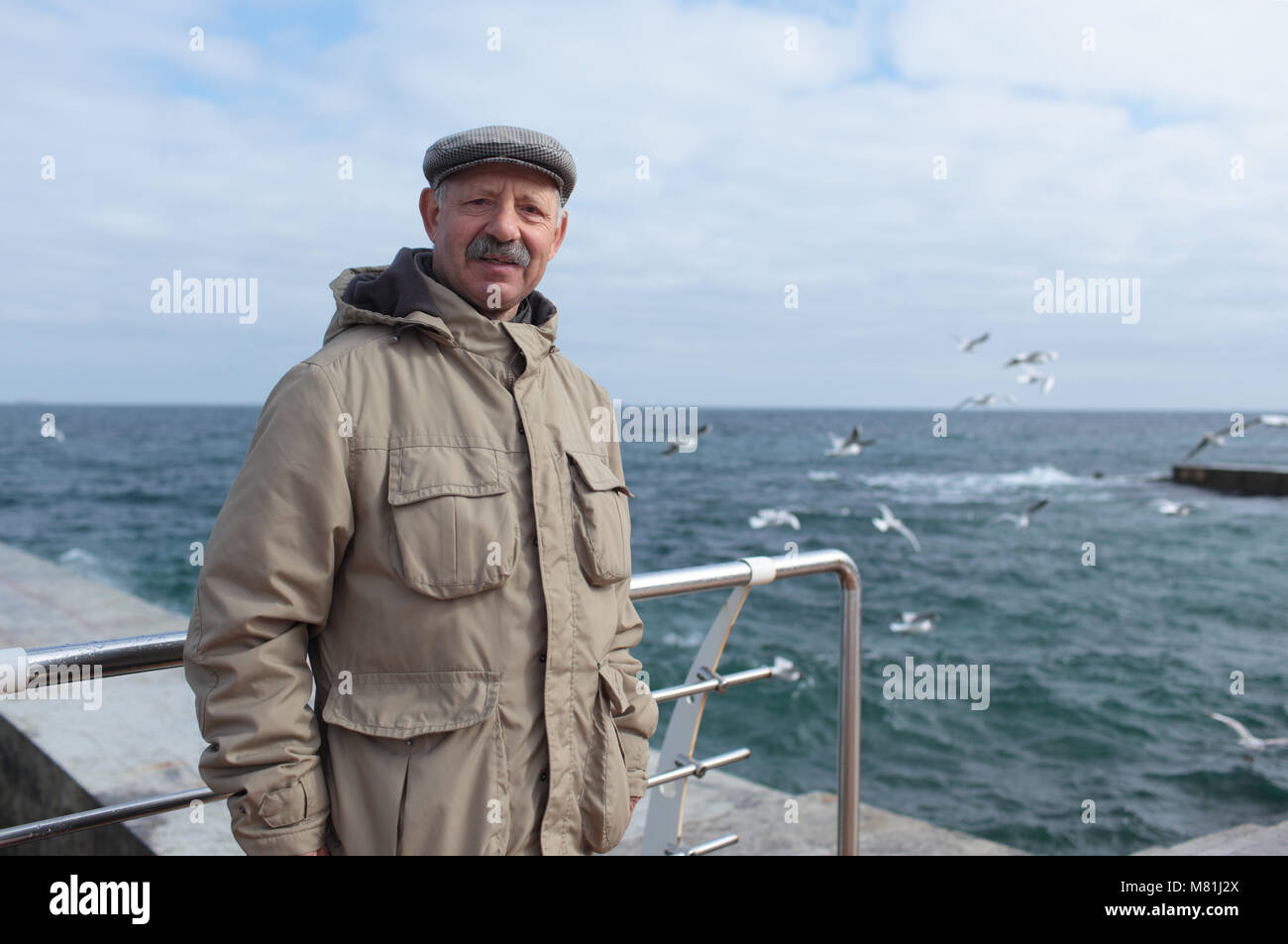 Ältere Mann auf der Pier vor dem Meer in einem Frühling Tag Stockfoto