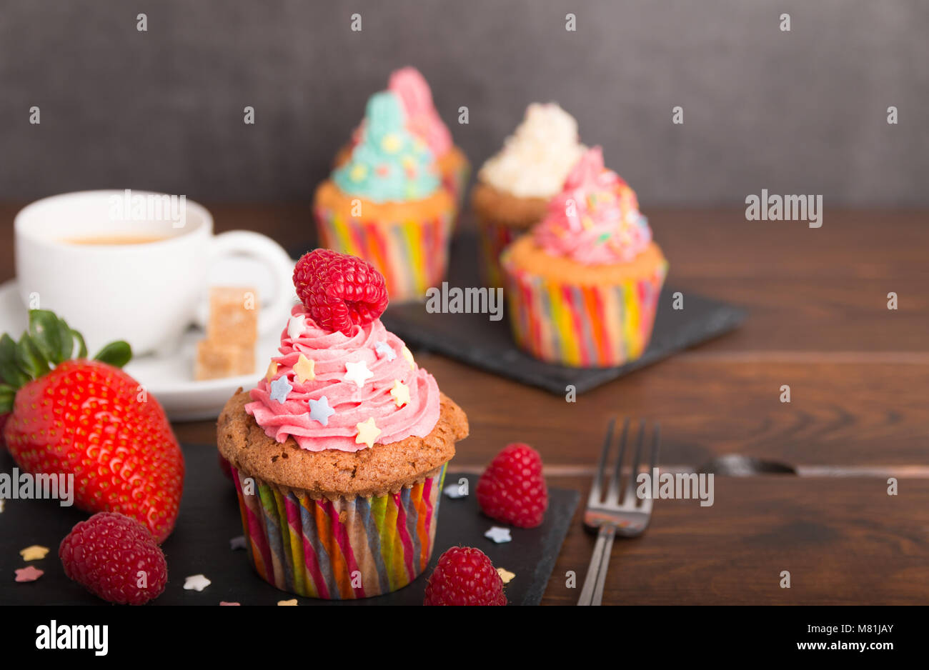 Selbst gebackene Muffins mit bunten Zuckerguss und Obst mit Kaffee ...