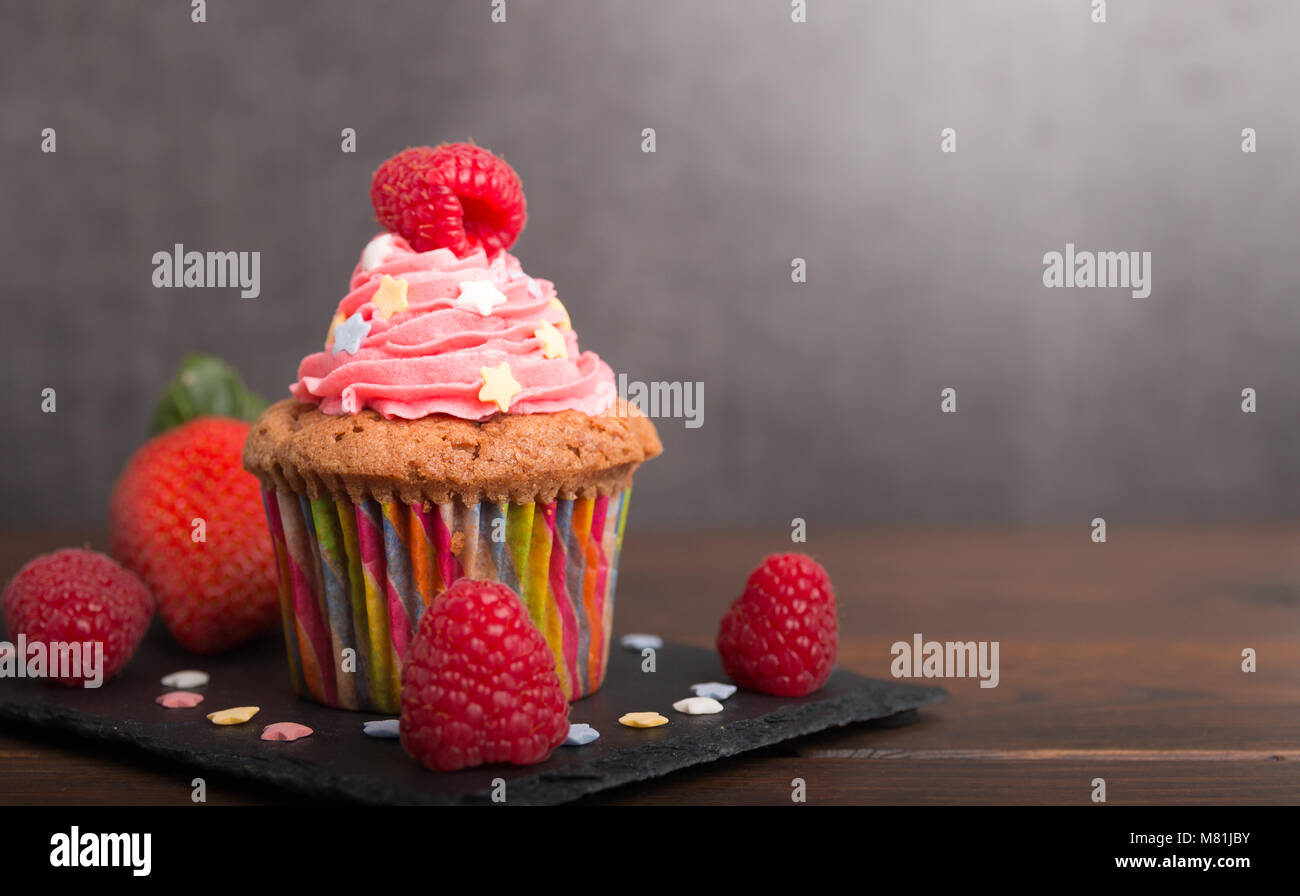 Selbst gebackene Muffins mit bunten Zuckerguss und Obst Nahaufnahme ...