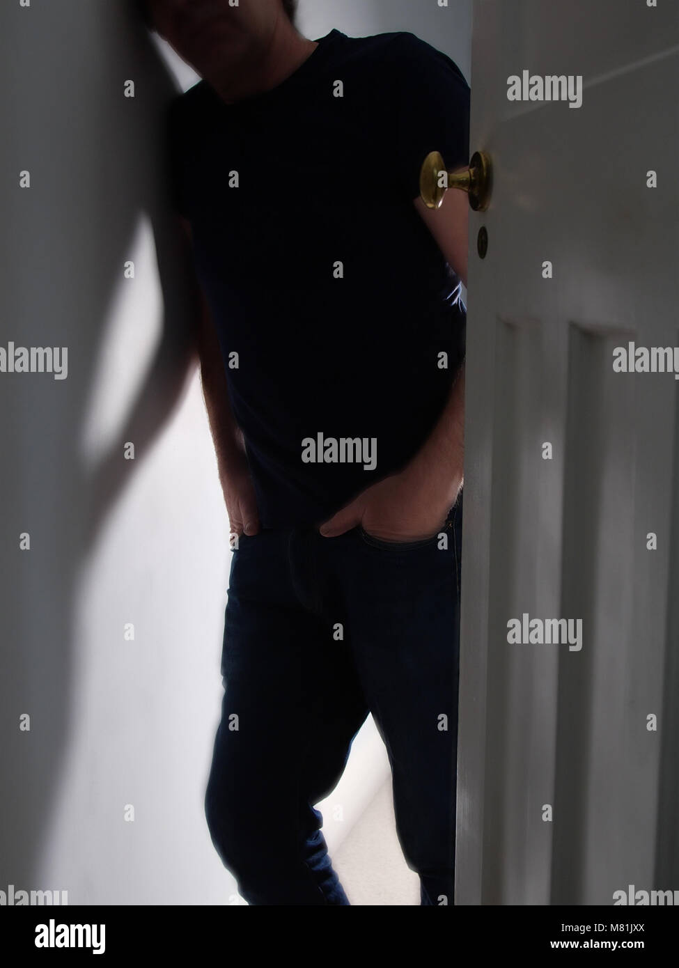 Nicht erkennbare Mann in einem Türrahmen, die Hände in den Taschen. Depression. Stockfoto