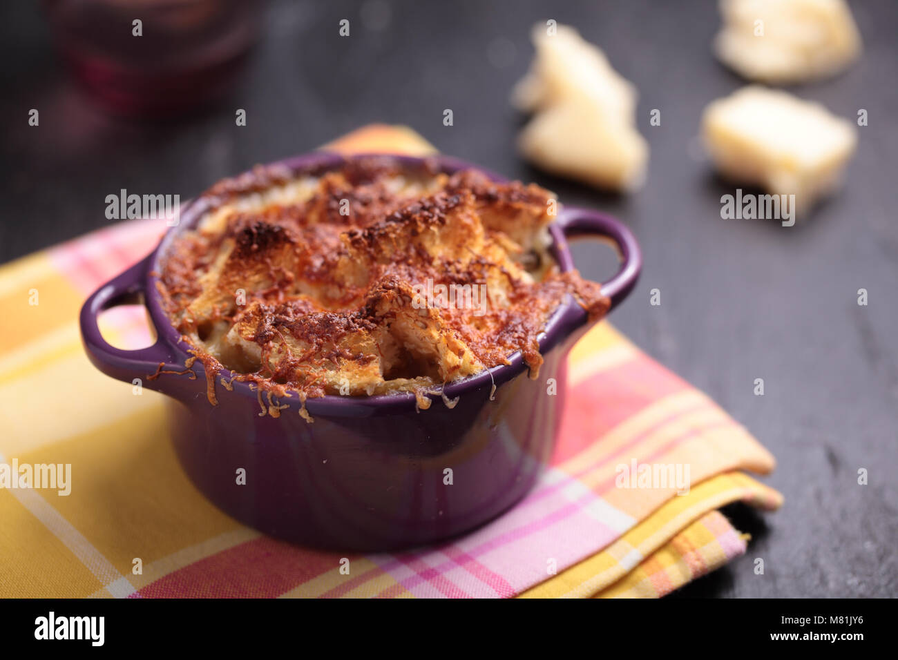 Zwiebelsuppe in einem violetten Keramiktopf mit Croutons und Parmesankäse Stockfoto