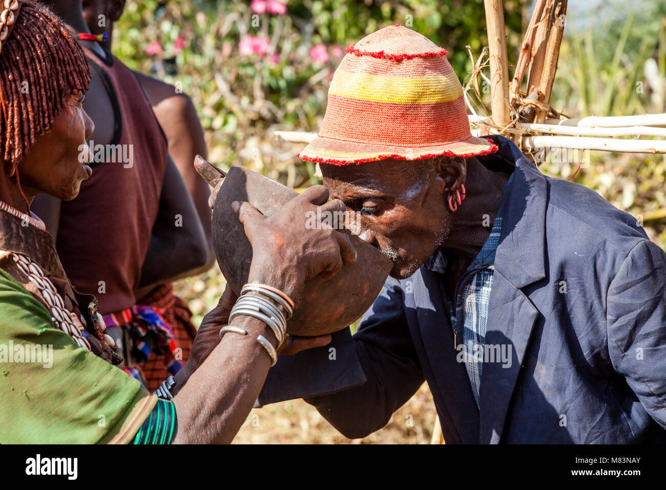 Ehrengäste an einen Stier springen Zeremonie werden Angeboten ein lokal gebrautes Bier zu trinken, Dimeka, Omo Valley, Äthiopien Stockfoto