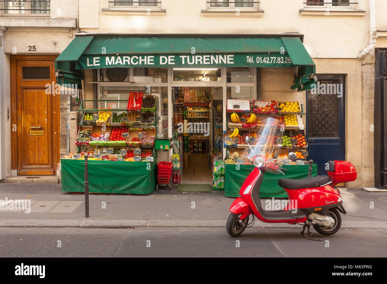 Kleines Lebensmittelgeschäft in Paris. Red Motorroller steht vor. Stockfoto