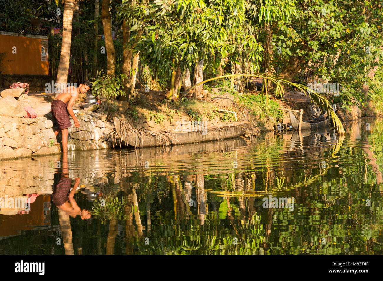 Ein junger Mann am Wasser auf die Kerala Backwaters in der Nähe von Kumarakom, Kerala, Indien. Stockfoto