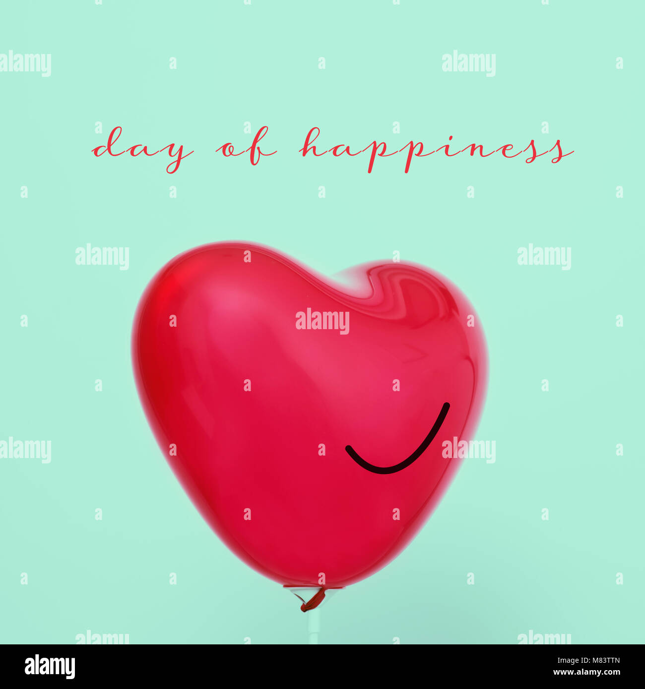 Der text Tag des Glücks und eine rote herzförmige Ballons mit einem Lächeln in es gezeichnet, gegen einen hellgrünen Hintergrund Stockfoto