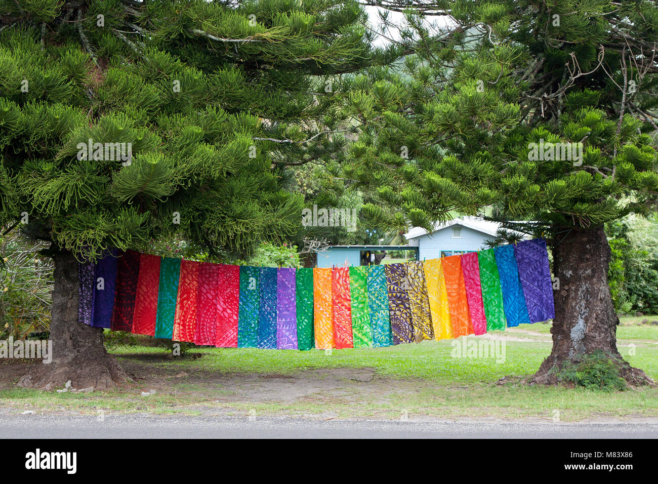 Die Farben des Regenbogens, bunte Material zwischen zwei Bäumen aufhängen in den Cook Island South Pacific zu trocknen. Stockfoto