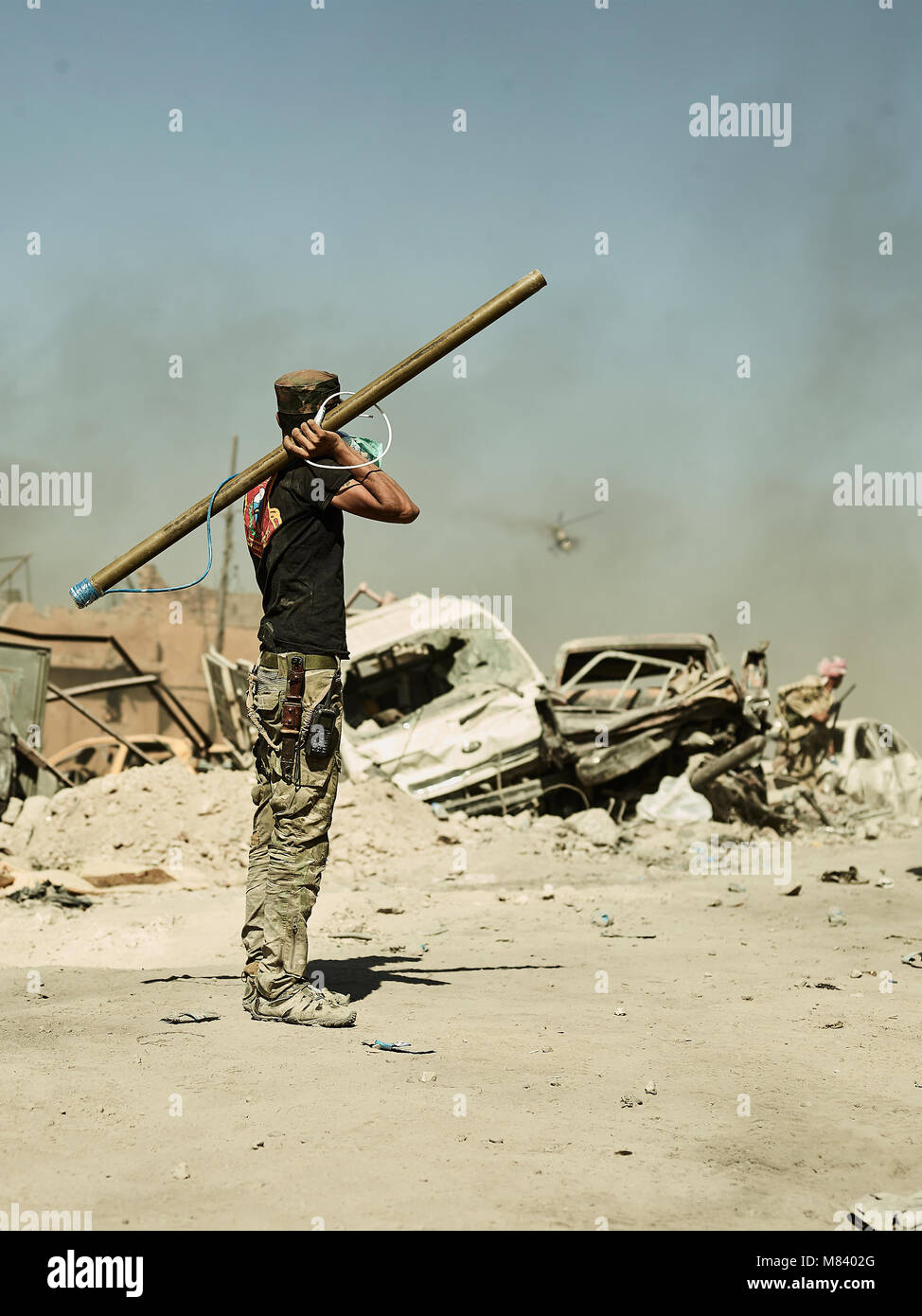 Ein irakischer Soldat sieht sich als beschädigt Kampfhubschrauber macht einen strafing Run gegen islamische militante entlang des Tigris. Die Stadt Mosul im Nordirak hat unter islamischen Staat militanten wurde für 3 Jahre, seit Juni 2014. Im Juli 2017 die Streitkräfte der Koalition geführt von der irakischen Armee hat endlich befreit die Stadt aus der Hand von Terroristen. Stockfoto