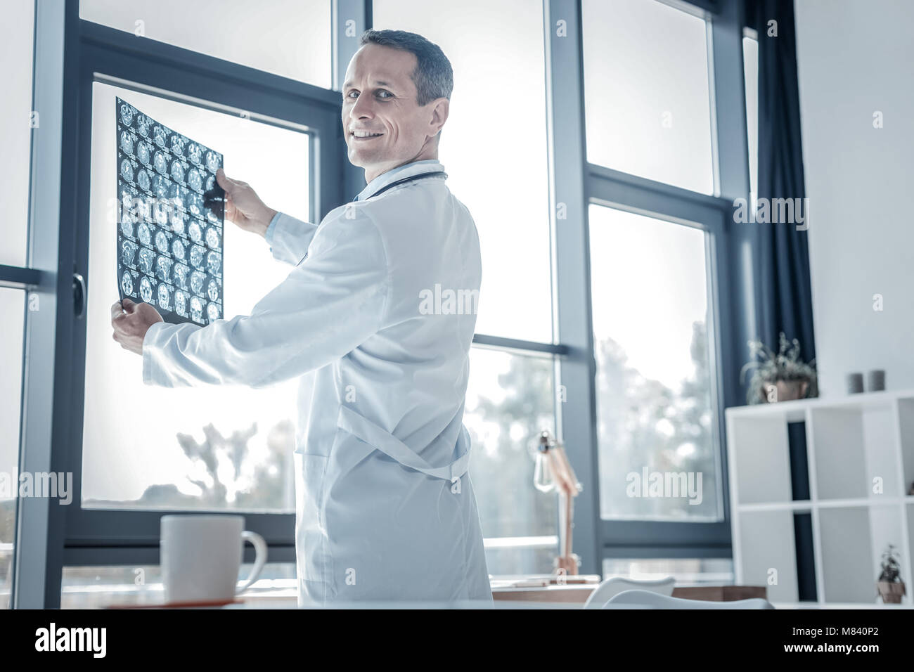 Zufrieden angenehm Arzt Holding x-ray Scan und lächelnd. Stockfoto